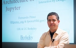 Photo of Fernando Perez in front of projected image of a presentation slide 