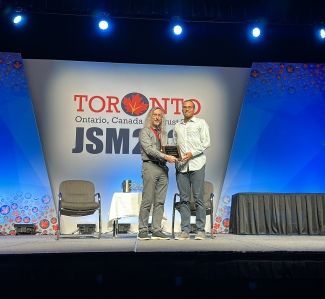 Ryan Tibshirani receiving award on stage at JSM