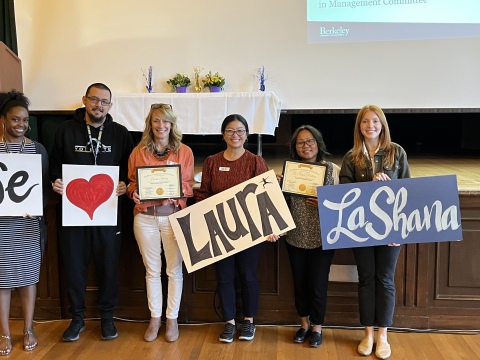 Photo of staff at EIM awards ceremony holding signs we heart Laura La Shana